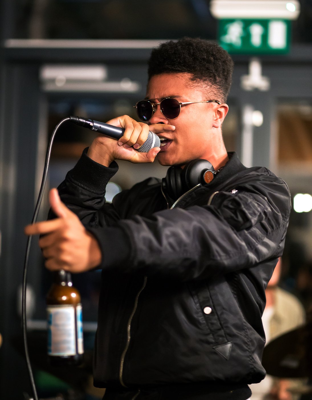 Black rapper performing with microphone, holding bottle.